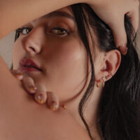 Élégant embout en or avec moissanite à l'oreille Gros plan d'une femme avec un embout en or 14K avec moissanite à l'oreille, arrière-plan flou