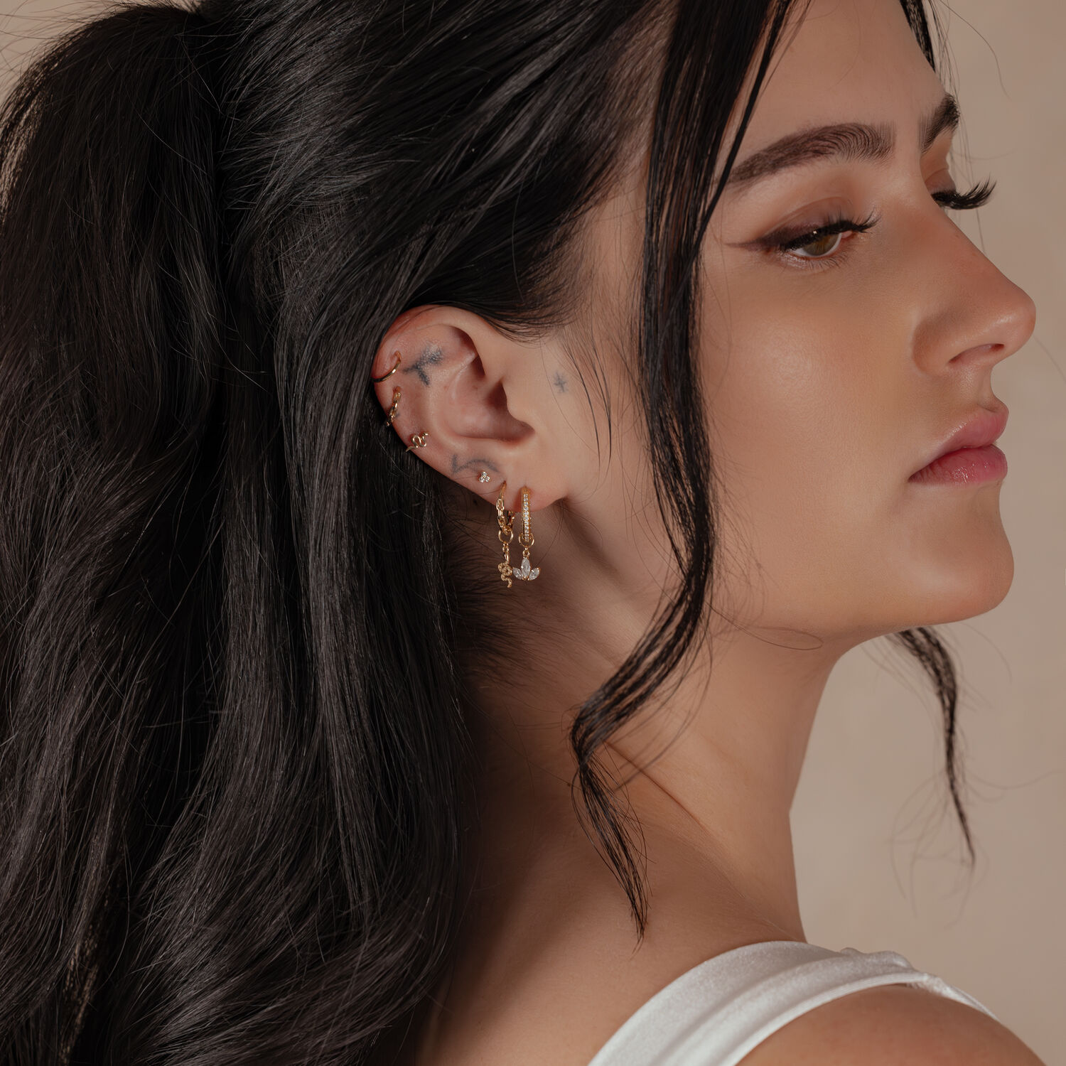 Anneau de piercing en or 18K porté à l'oreille Femme avec anneau articulé en or 18K à l'oreille, profil latéral, cheveux foncés