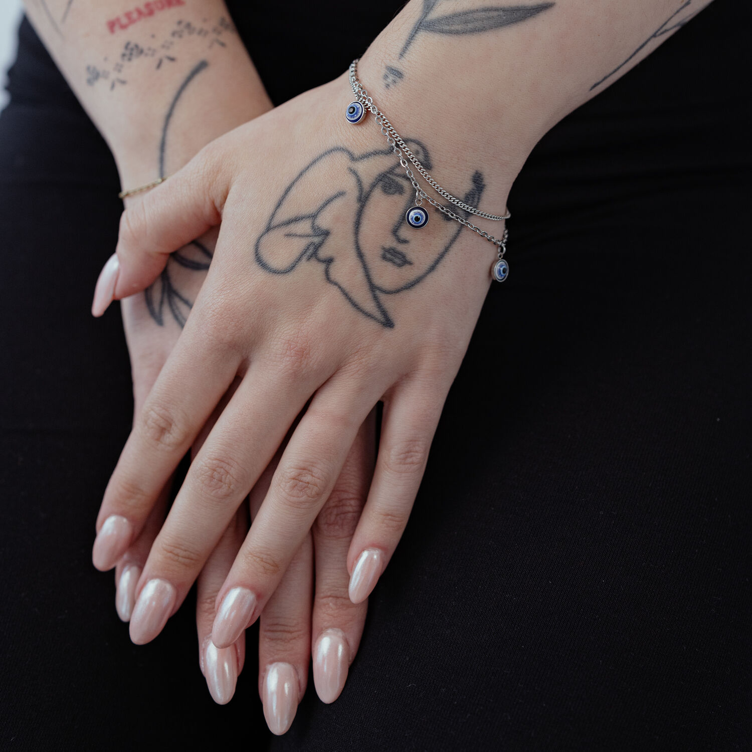 Deux mains avec le bracelet Little Nazar sur fond noir