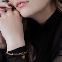 Femme avec bracelet cœur doré sur fond noir