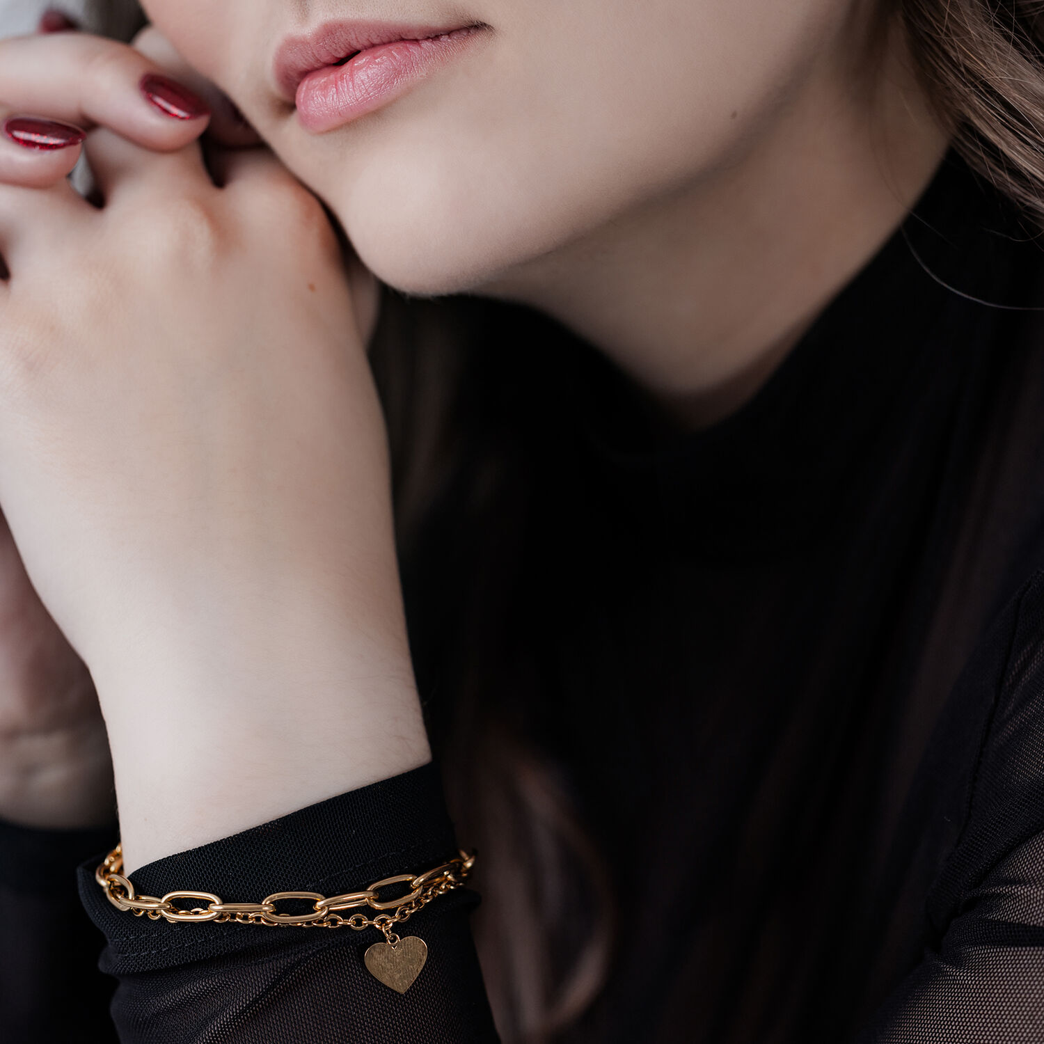 Femme avec bracelet cœur doré sur fond noir