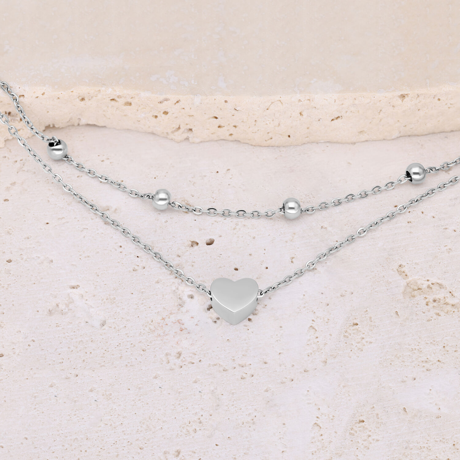 Bracelet argenté à double rangée avec cœur et perles sur fond clair