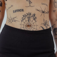 Clicker de nombril en titane noir avec cristal clair sur peau tatouée