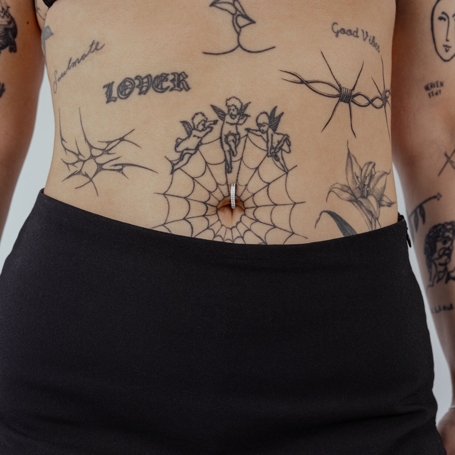 Clicker de nombril en titane noir avec cristal clair sur peau tatouée