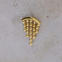 Embout de piercing hélix doré avec boules pendantes sur fond clair