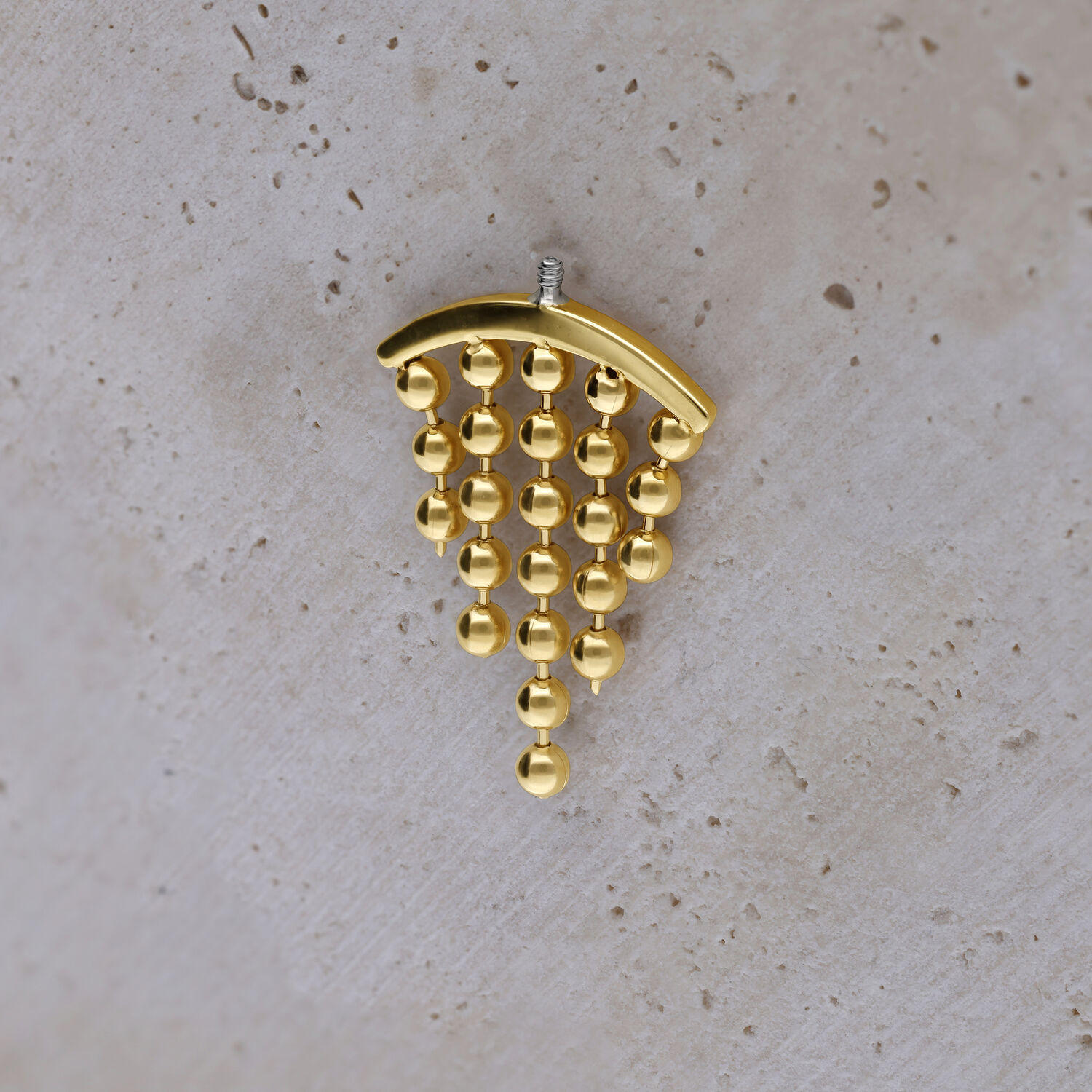 Embout de piercing hélix doré avec boules pendantes sur fond clair