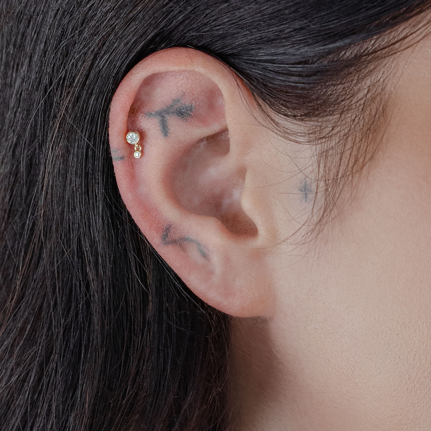 14K Or Double Cristal Piercing Embout Embout doré avec deux cristaux porté à l'oreille, gros plan