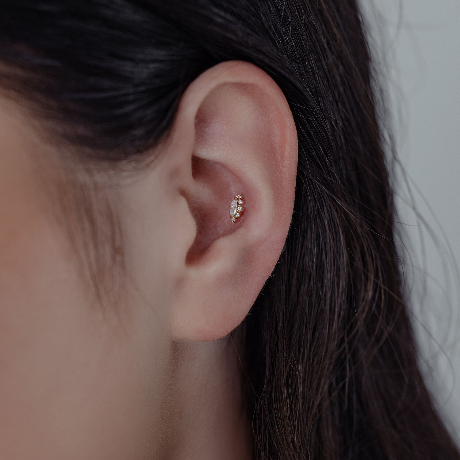 Gros plan d'une oreille avec embout en or 14K Moissanite sur fond neutre