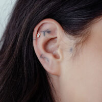 Piercing d'oreille Lotus Opale en or 14K Gros plan d'un piercing d'oreille avec Lotus en or 14K et opale synthétique sur une oreille