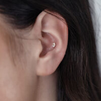 14K Or Fleur Opale Embout à l'Oreille Gros plan d'une oreille avec un embout en or 14K fleur opale