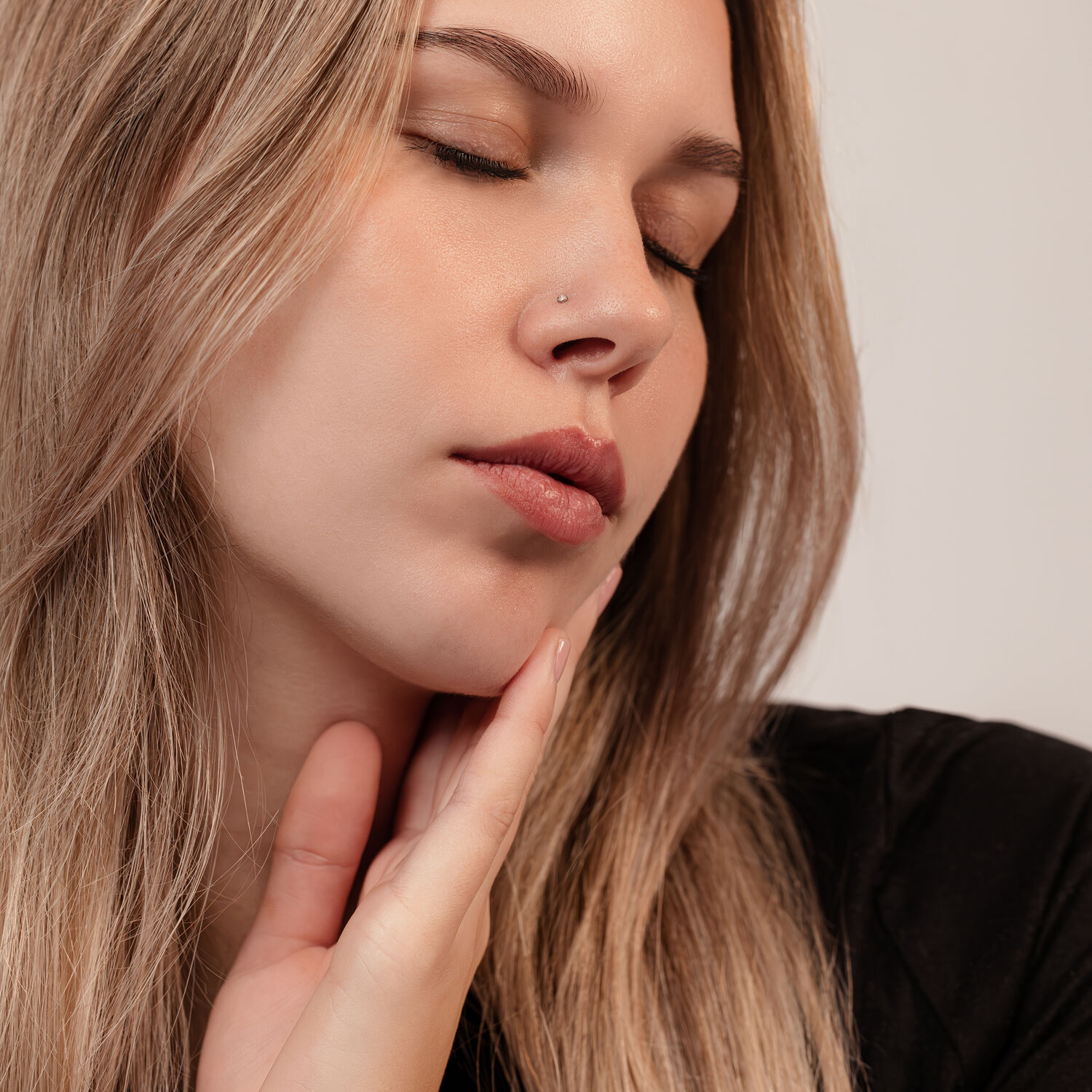 Clou de nez élégant en titane noir Femme avec œil fermé, portant un clou de nez élégant en titane noir