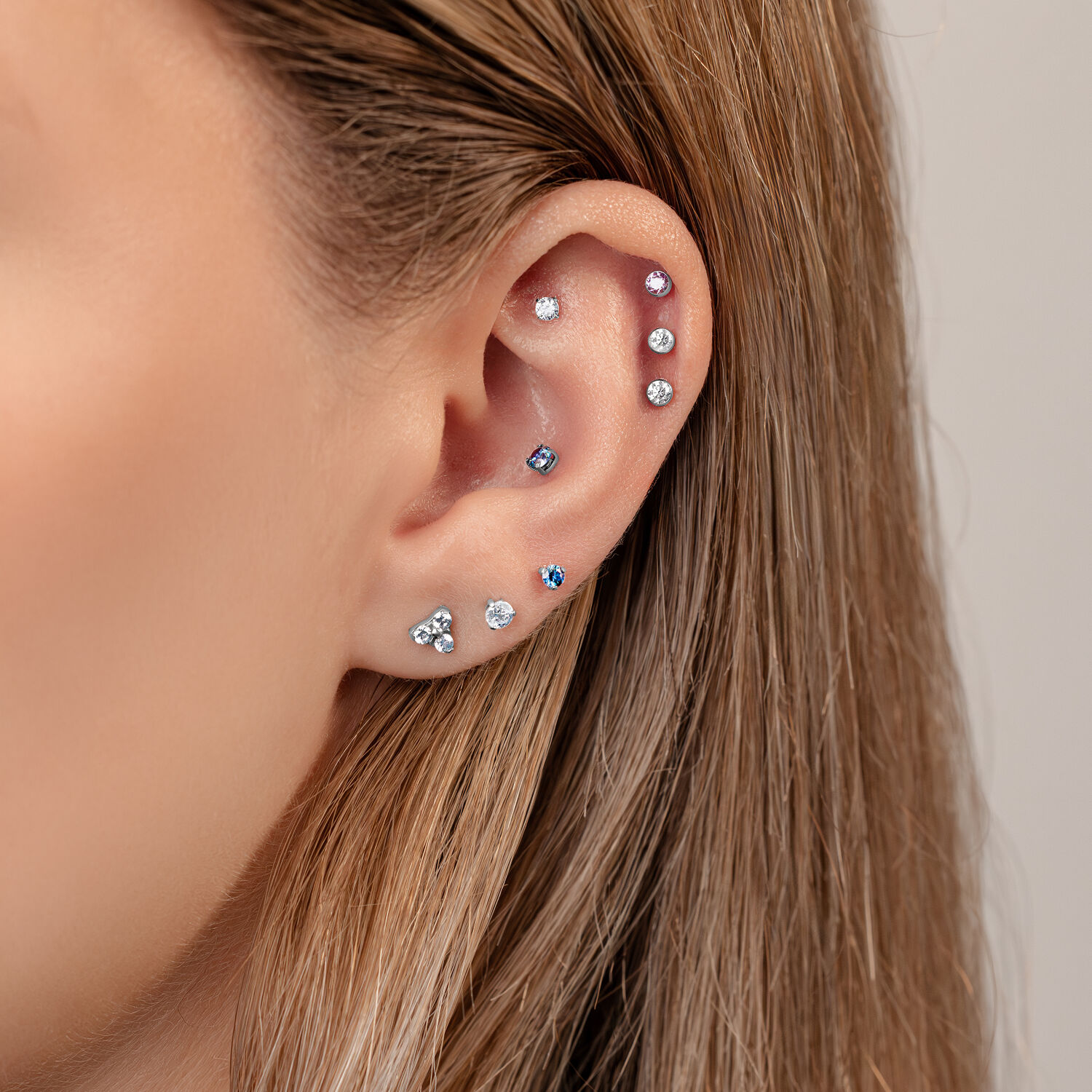 Embout 3 griffes en couleur cristal pour Push Fit Gros plan d'une oreille avec plusieurs piercings, y compris un embout 3 griffes en couleur cristal