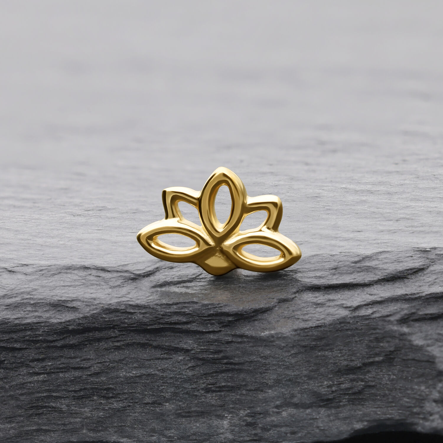 Embout Lotus en Or 14K pour Piercings Embout Lotus doré sur pierre grise avec lignes claires et surface brillante