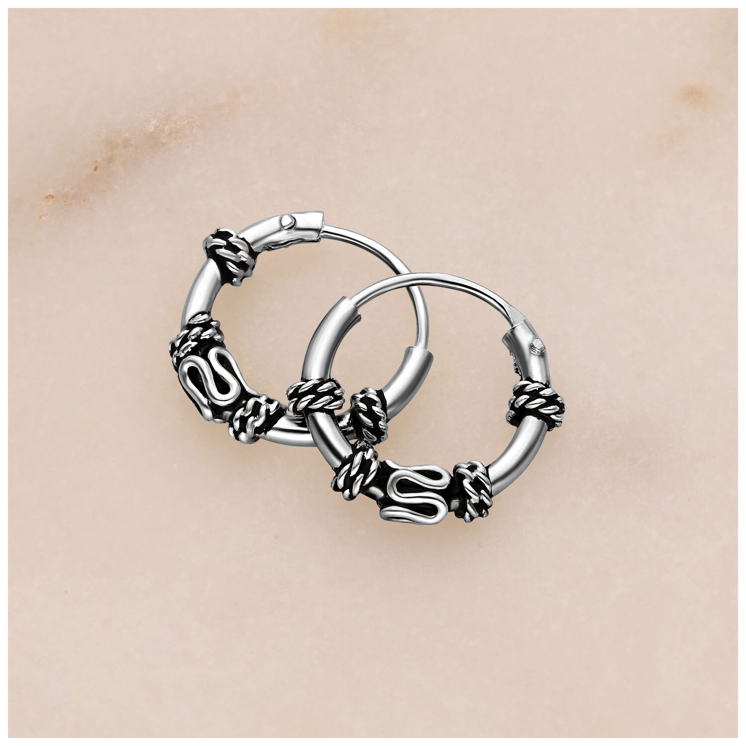 Créoles argentées avec design de nœud Créoles argentées avec détails de nœud sur fond clair