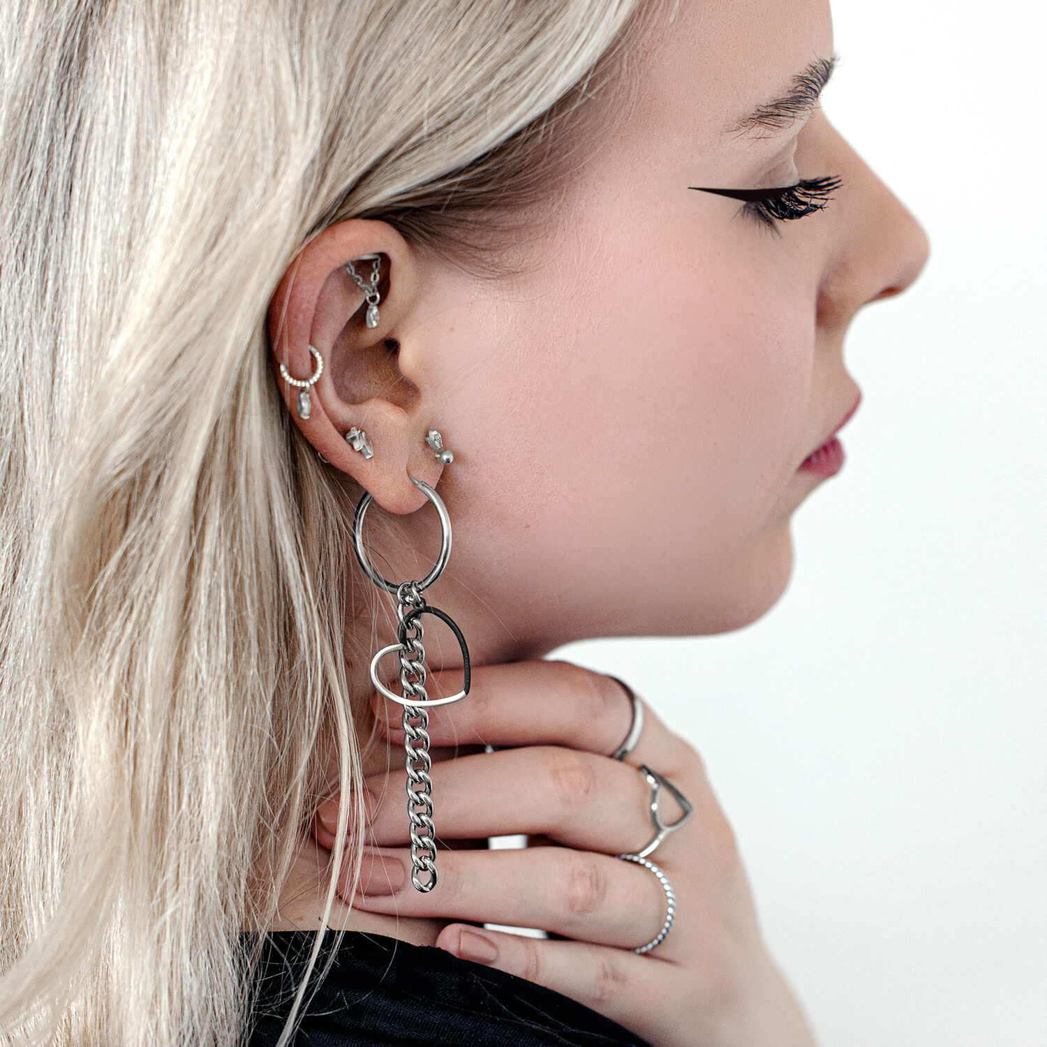 Créoles cœur bicolores à l'oreille d'une femme Créoles cœur en argent et or à l'oreille d'une femme aux cheveux blonds
