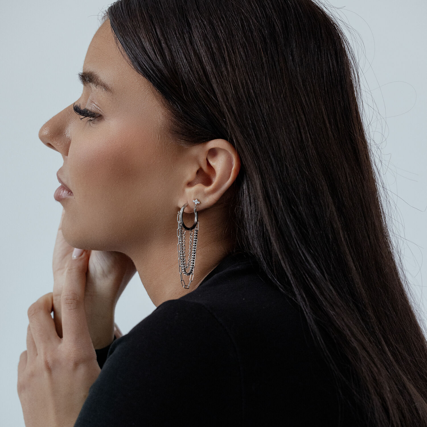 Boucles d'oreilles modernes à chaînes multicouches Femme aux cheveux noirs portant des créoles à chaînes multicouches argentées sur fond clair