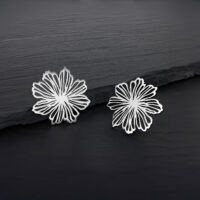 Fins clous d'oreilles fleurs en acier inoxydable Deux clous d'oreilles fleurs en argent en acier inoxydable sur fond sombre