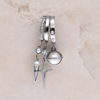 Trois boucles d'oreilles argentées avec pendentifs en perles et strass sur fond de marbre