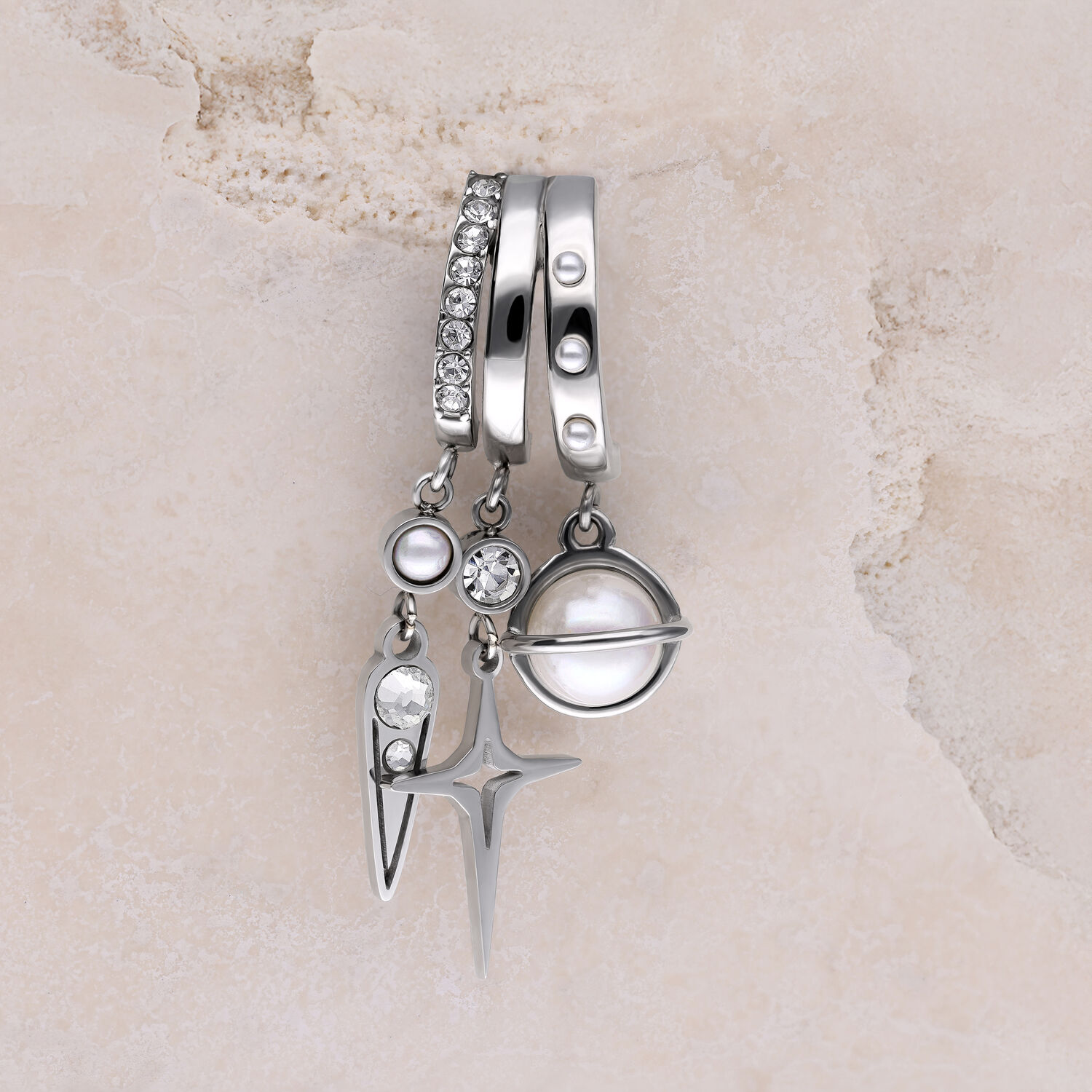 Trois boucles d'oreilles argentées avec pendentifs en perles et strass sur fond de marbre