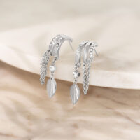 Boucles d'oreilles argentées avec pendentif feuille Boucles d'oreilles argentées avec pierres scintillantes et pendentifs feuilles sur surface en marbre