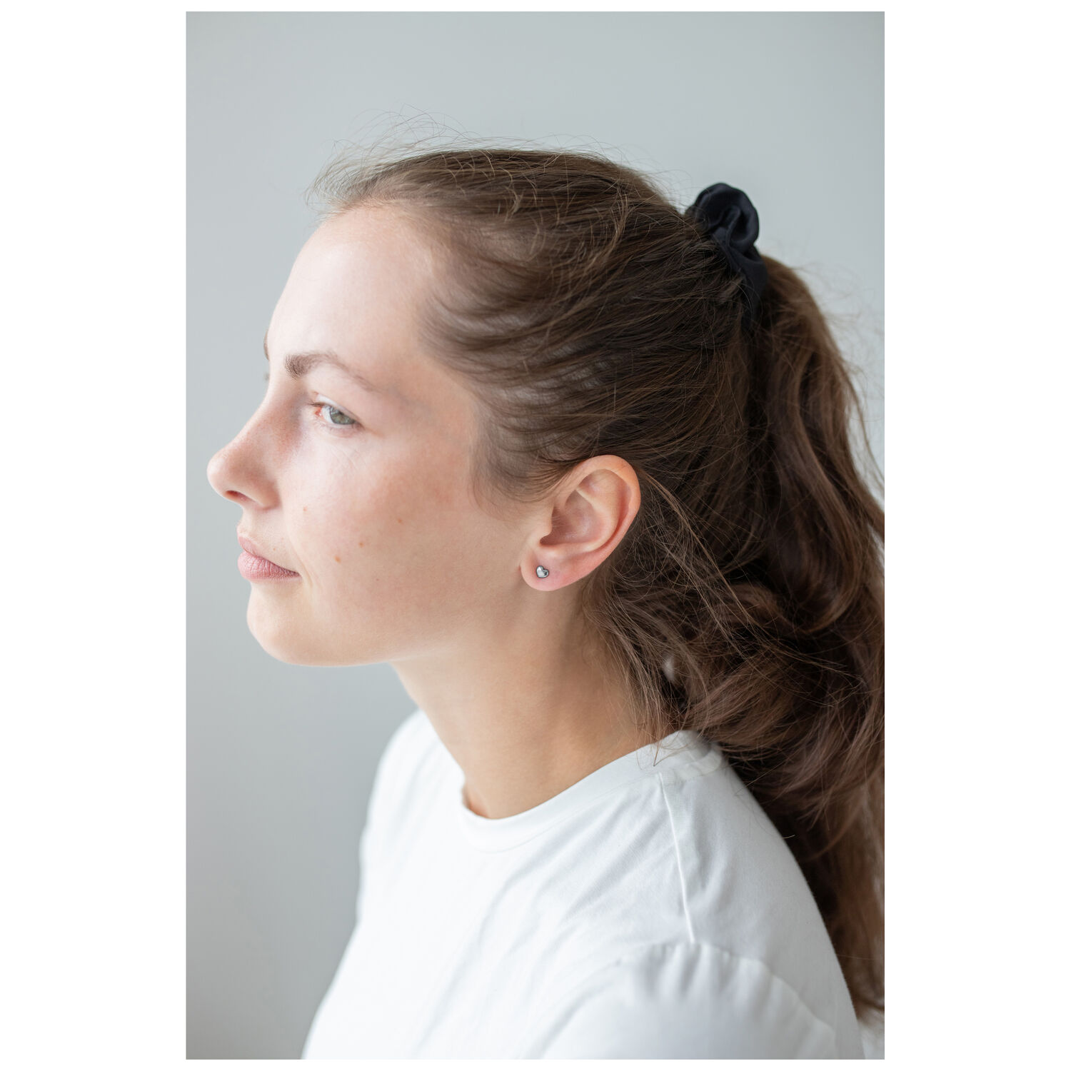 Femme avec boucles d'oreilles cœur en acier inoxydable, profil latéral
