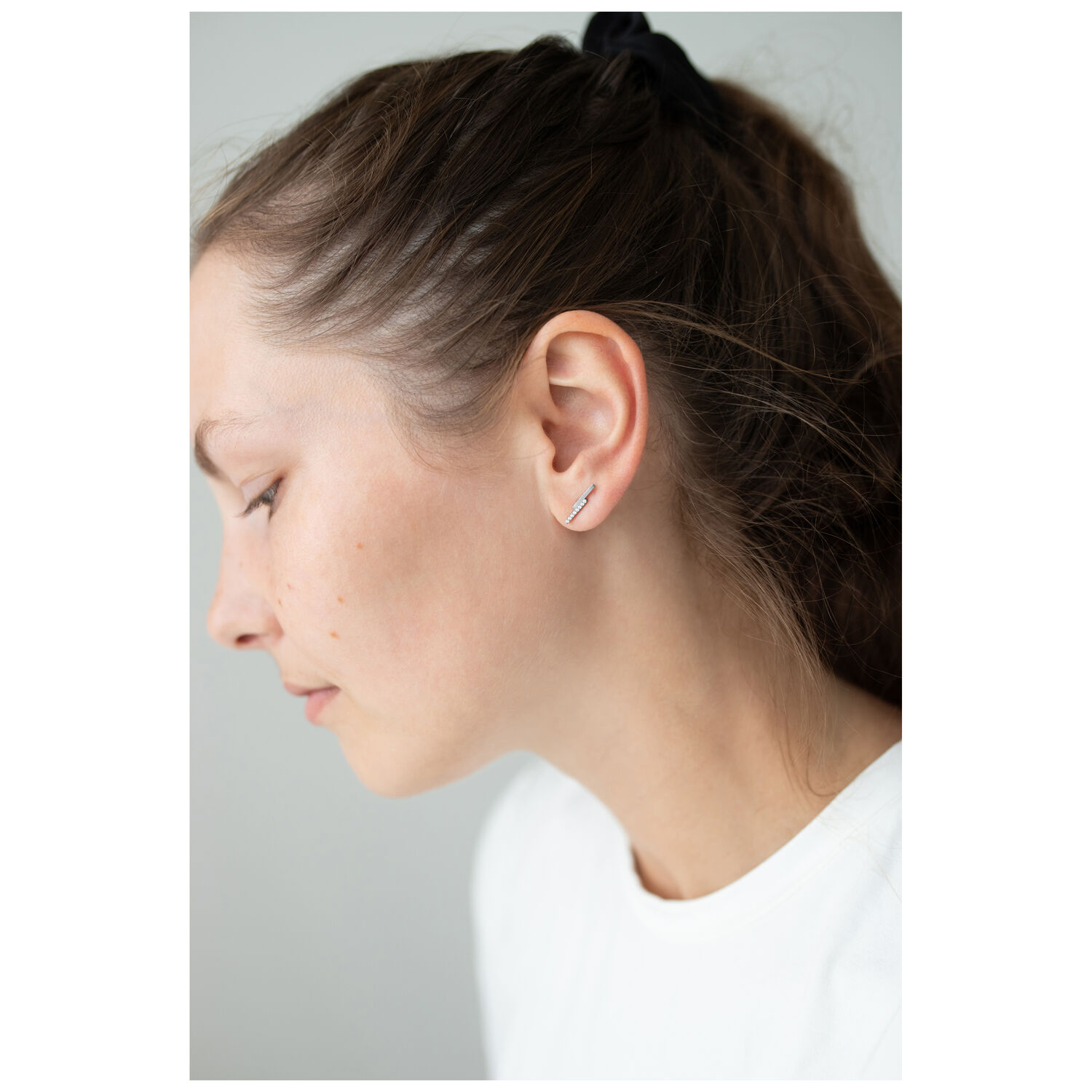 Boucles d'oreilles Double Beam Crystal accrocheuses Boucles d'oreilles en argent avec cristaux sur l'oreille d'une femme sur fond neutre