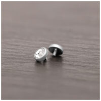 Embout de piercing en titane argenté avec cristal Embout de piercing en titane argenté avec cristal clair sur surface en bois