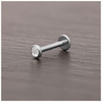 Embout de piercing en titane argenté avec cristal Embout de piercing en titane argenté avec cristal clair sur surface en bois sombre