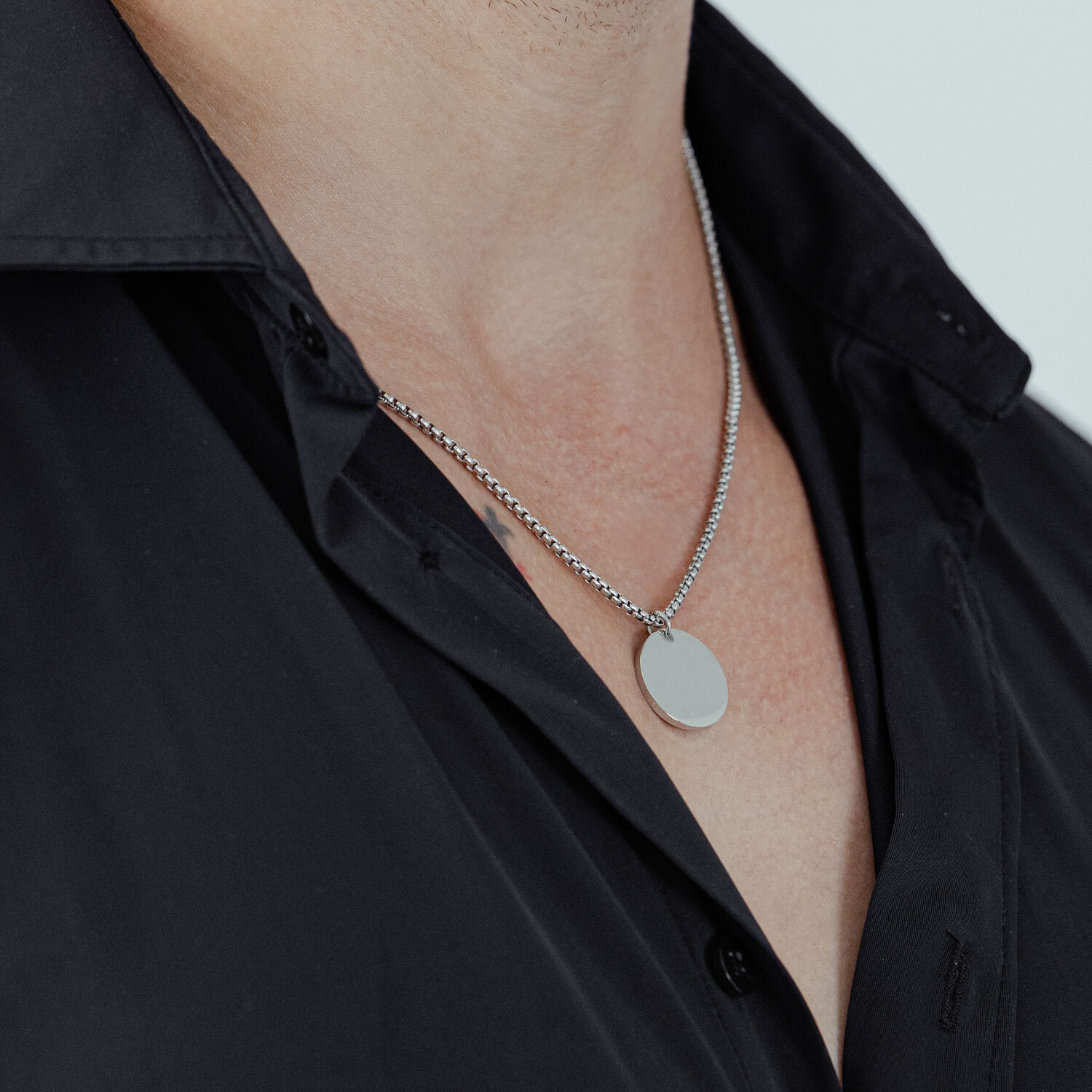 Chaîne de base gravable en acier chirurgical Chaîne argentée avec pendentif rond sur une chemise noire