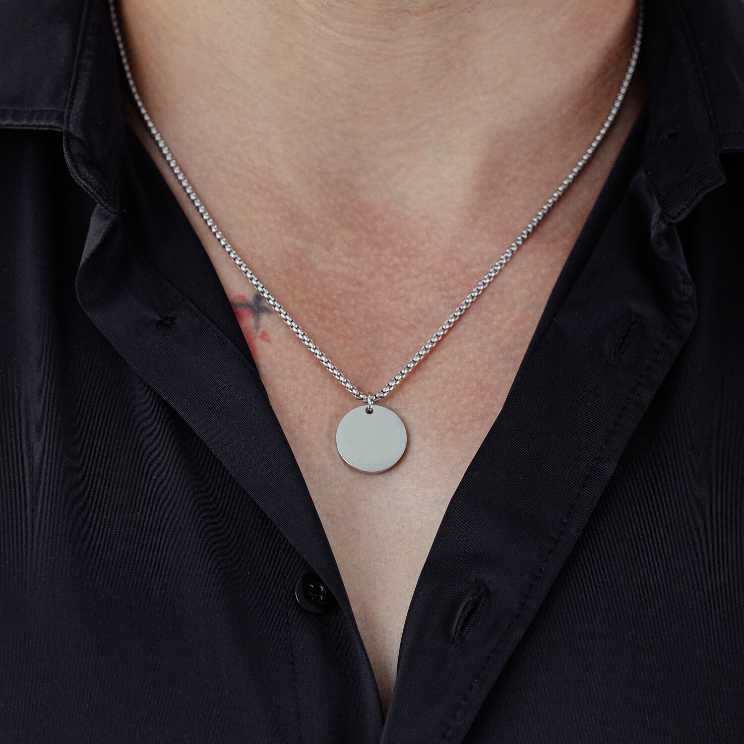 Chaîne basique gravable en acier chirurgical Chaîne argentée avec pendentif rond portée sur une chemise noire