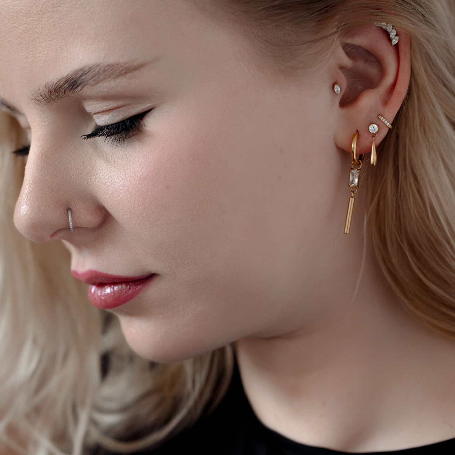 Embout de piercing en cristal élégant pour l'oreille Femme avec plusieurs piercings, y compris un embout de piercing en cristal doré dans l'oreille.