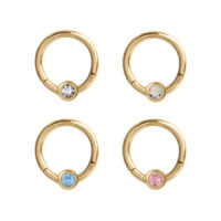Clicker en cristal doré avec cristaux colorés Quatre anneaux de piercing dorés avec des cristaux clairs, bleus, roses et chatoyants sur fond blanc
