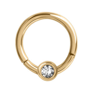 Anneau de piercing doré avec cristal clair sur fond blanc