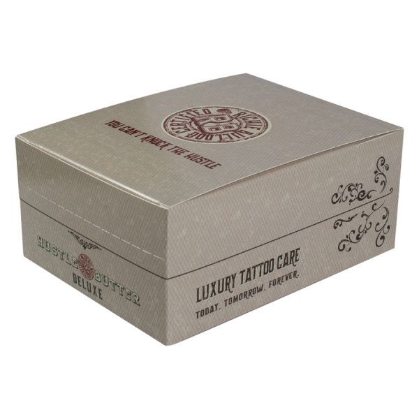 Hustle Butter Deluxe Box pour soin des tatouages Boîte beige avec logo Hustle Butter Deluxe et décorations