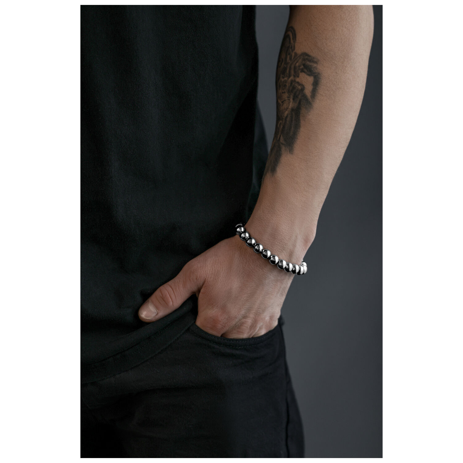 Bracelet Bubble argenté au poignet Bracelet Bubble argenté sur un poignet tatoué devant un fond gris