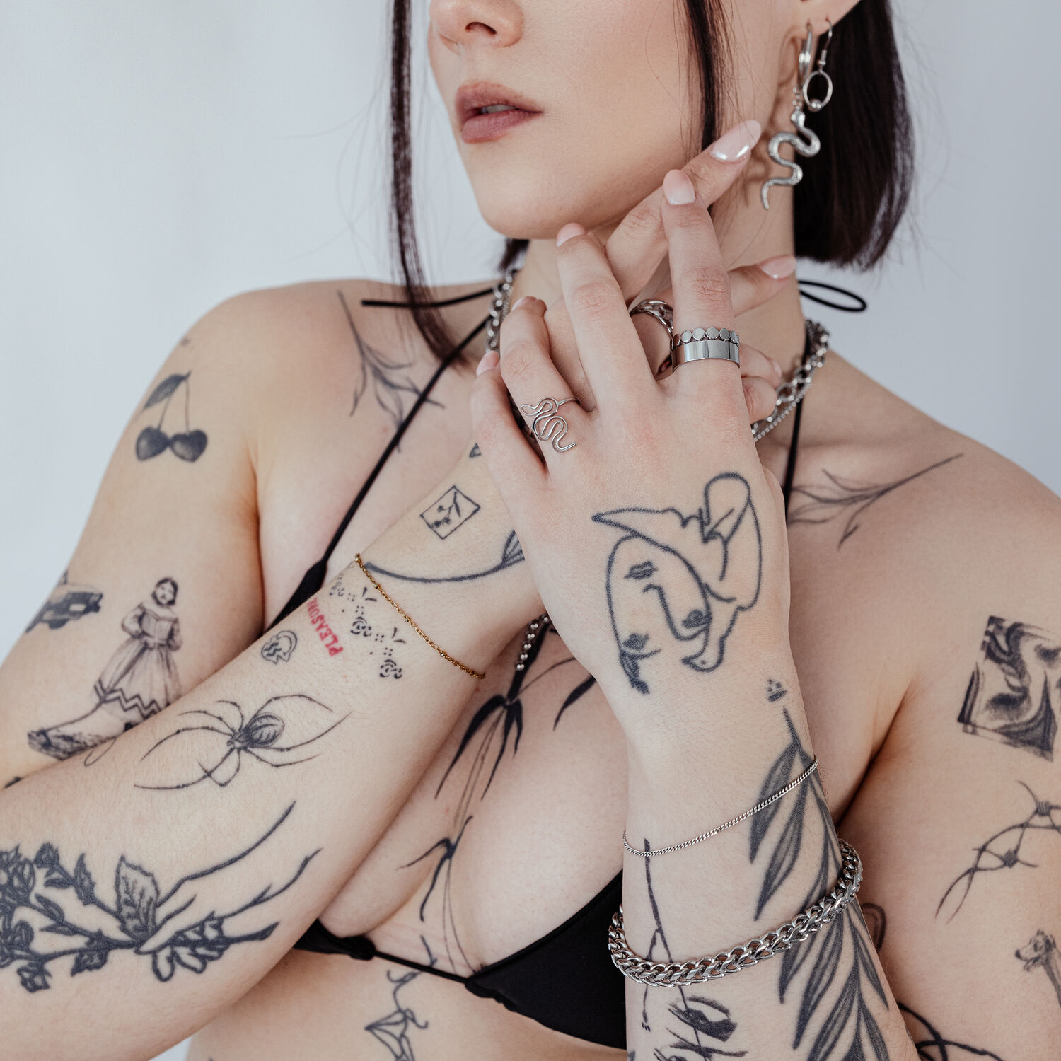 Femme aux bras tatoués portant un bracelet tressé argenté