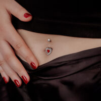Sacred Heart Bananabell en titane noir Femme avec vernis rouge montrant le Sacred Heart Bananabell dans le nombril