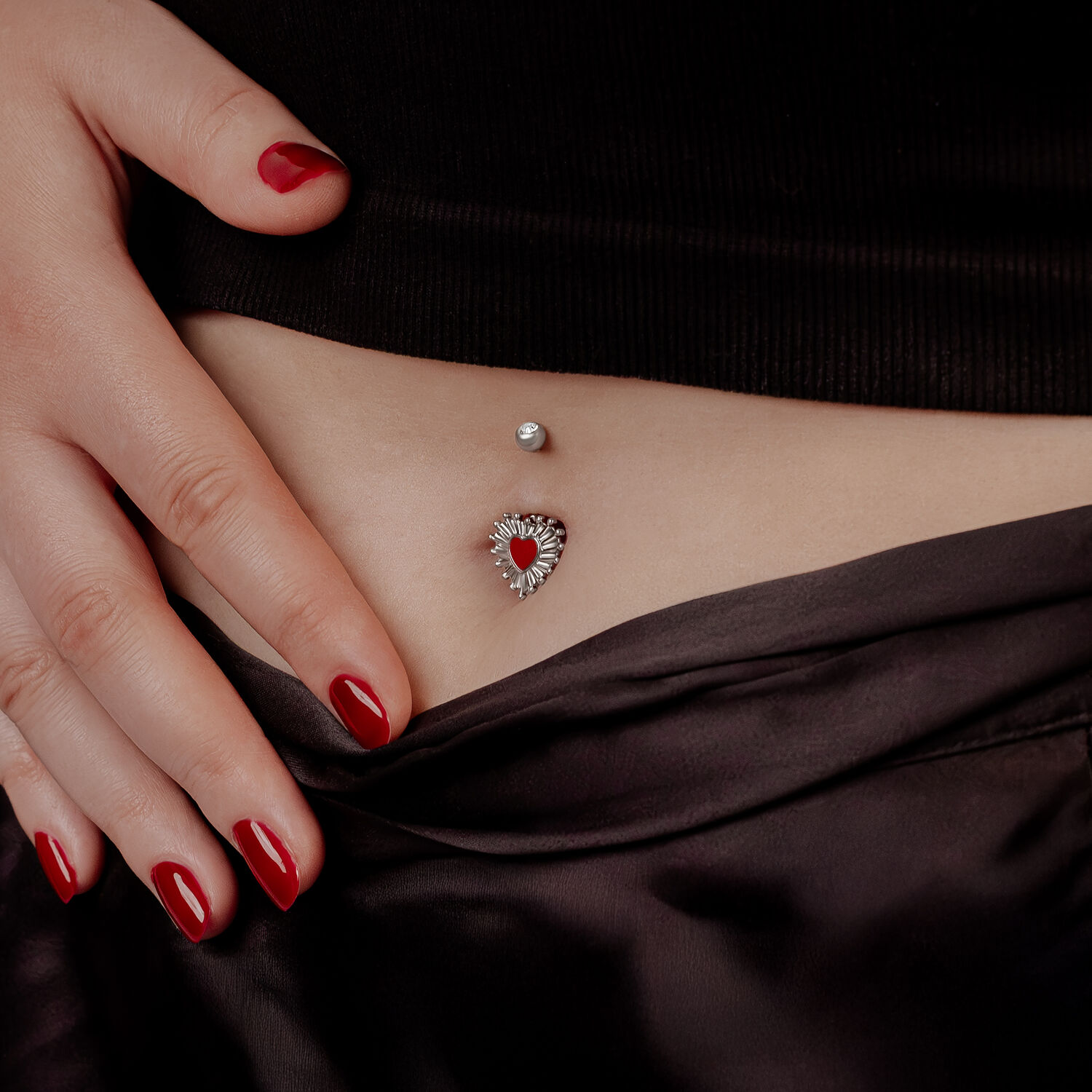 Sacred Heart Bananabell en titane noir Femme avec vernis rouge montrant le Sacred Heart Bananabell dans le nombril