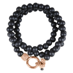 Bracelet en bois noir enroulé trois fois avec fermoir doré sur fond blanc