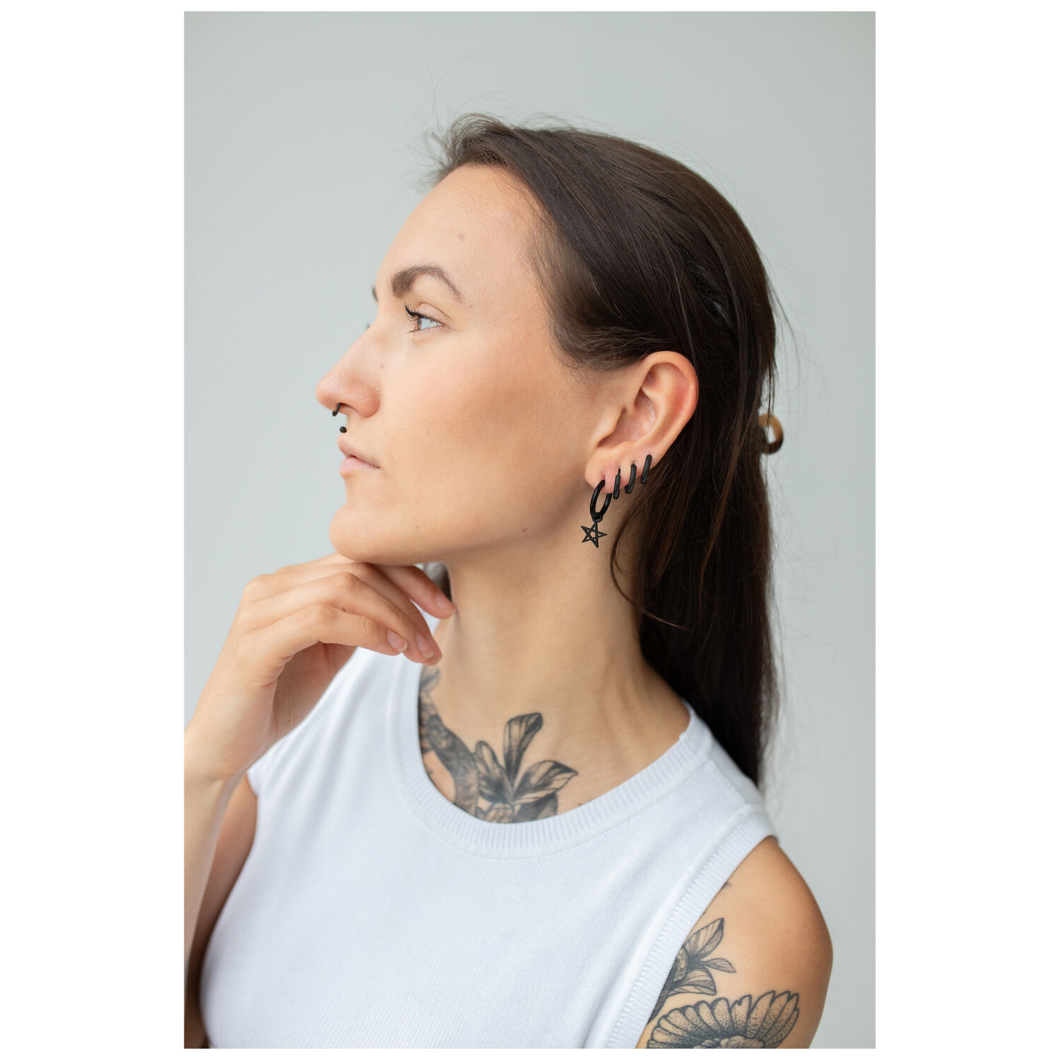 Boucles d'oreilles pentagramme noires à l'oreille Femme avec des boucles d'oreilles pentagramme noires sur fond gris