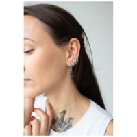 Élégantes Little Moonchild Hoops en noir Femme portant des Little Moonchild Hoops noires, portées de côté dans l'oreille