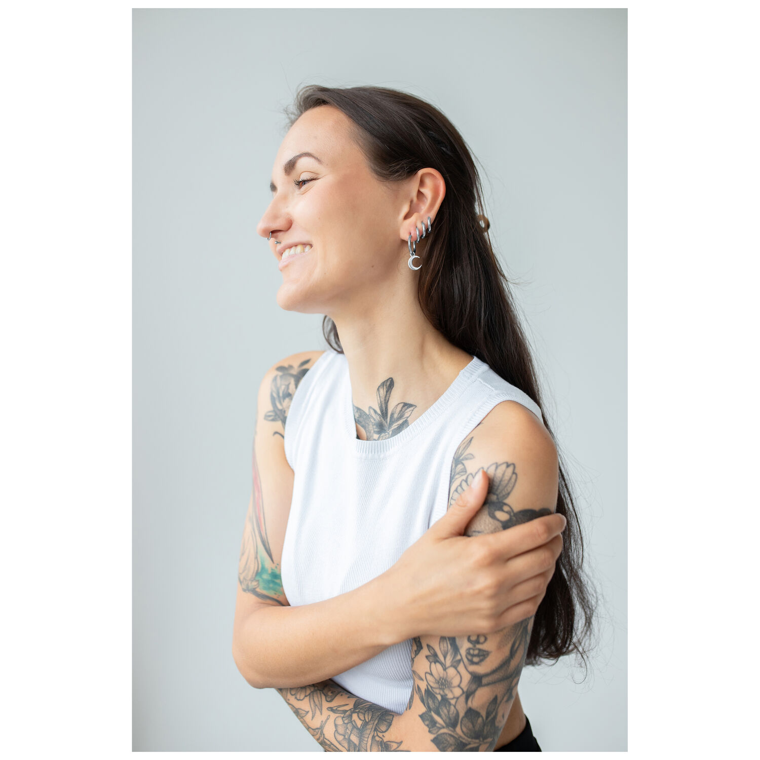 Créoles argentées Little Moonchild à l'oreille Femme aux bras tatoués portant des créoles argentées Little Moonchild