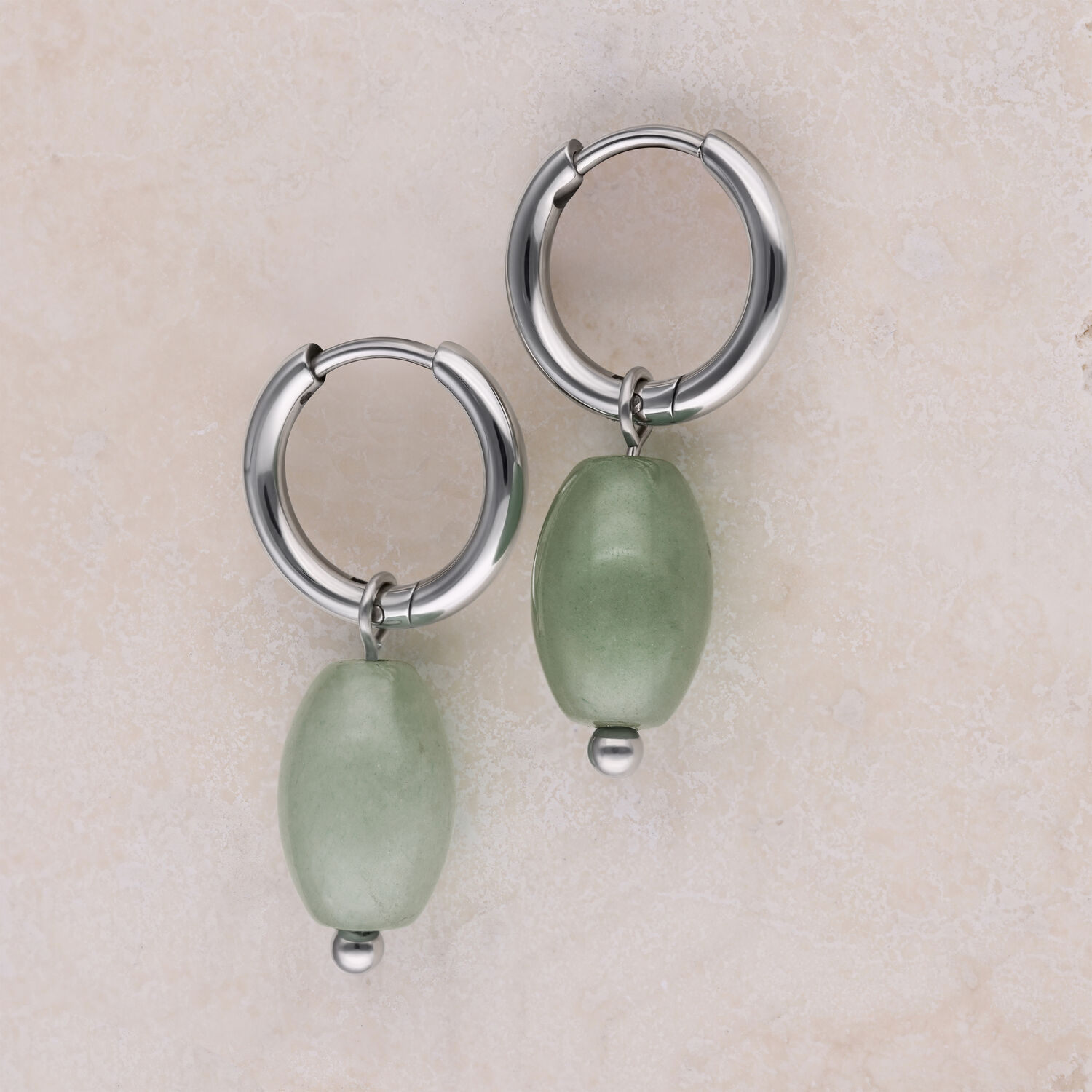 Créoles en acier inoxydable avec aventurine verte Deux créoles argentées avec pendentifs en aventurine verte sur fond clair