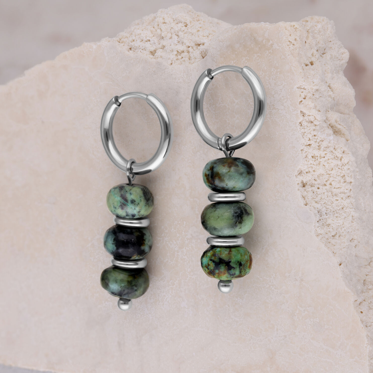 Deux créoles argentées avec des perles de turquoise africaine vertes sur une pierre claire