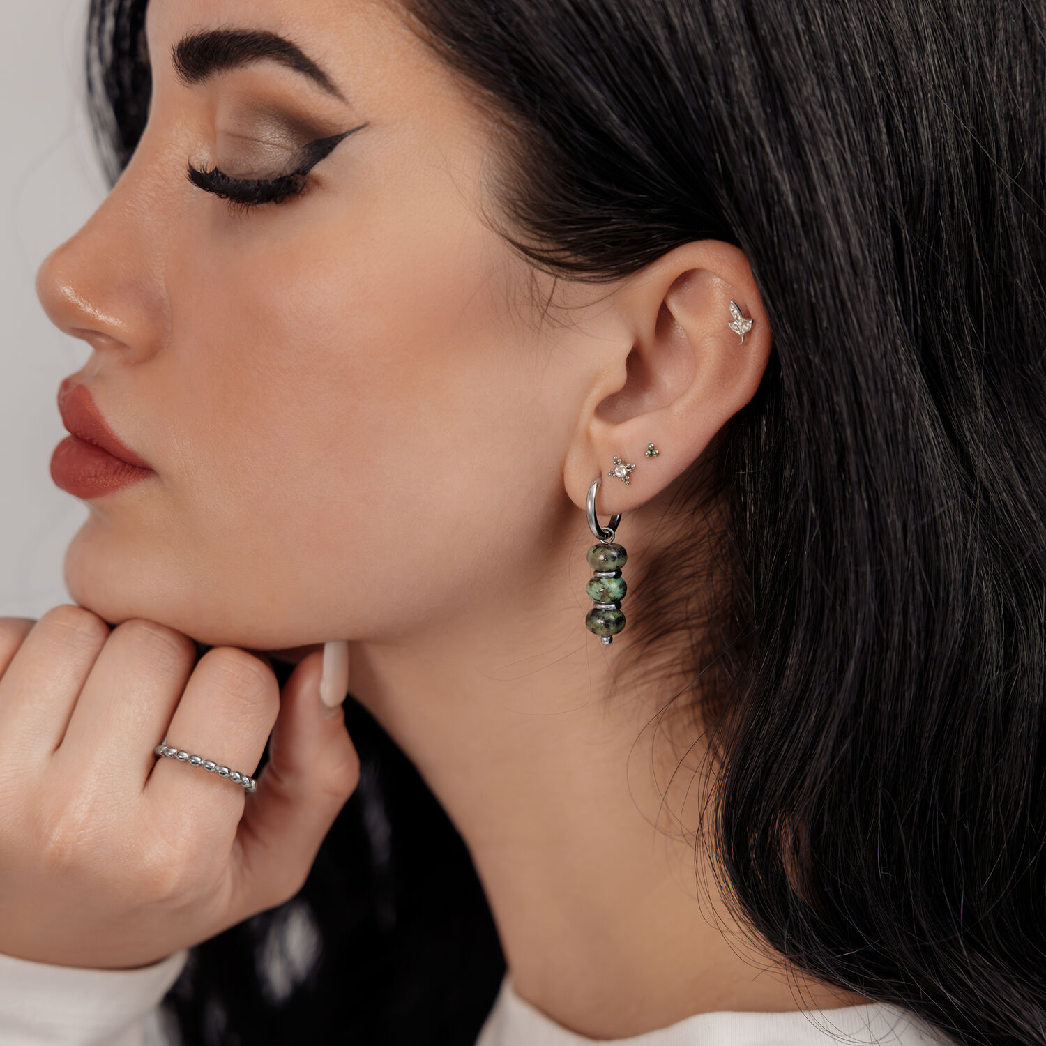 Boucles d'oreilles en turquoise africaine avec design à bulles Femme avec des boucles d'oreilles pendantes en argent et turquoise africaine sur fond neutre