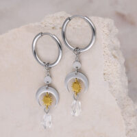 Créoles argentées avec soleils dorés et cristaux Créoles argentées avec pendentifs soleils dorés et cristaux clairs sur fond clair