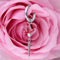 Boucle d'oreille argentée avec cristaux rouges, en forme de fleur, devant une rose rose