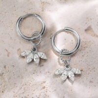 Boucles d'oreilles en cristal argenté avec pendentif Deux boucles d'oreilles argentées avec pendentifs en cristal clair sur une pierre claire