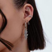 Boucles d'oreilles argentées avec design feuille Gros plan d'une oreille avec des boucles d'oreilles argentées au design feuille, plusieurs piercings