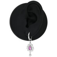 Boucles d'oreilles argentées avec pendentif en cristal rose Boucle d'oreille argentée avec pendentif en cristal rose sur un modèle d'oreille noir
